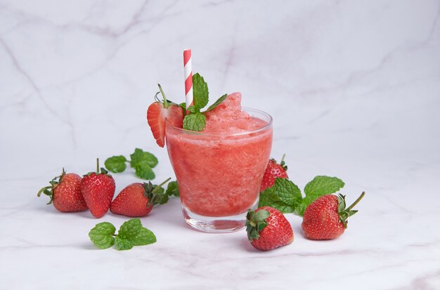 Smoothies Sommererdbeere trinken, Köstlicher Erdbeersmoothie garniert mit frischer Erdbeere und Minze im Glas. Weicher Fokus. schöne Vorspeise rosa Erdbeere, Wohlbefinden und Gewichtsverlustkonzept