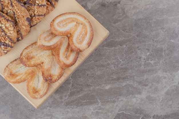 Snack-sortiment mit verschiedenen keksen auf einem kleinen brett auf marmor