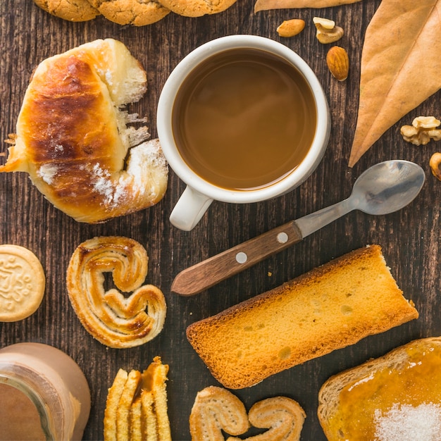 Snacks und Blatt in der Nähe von Kaffee und Löffel