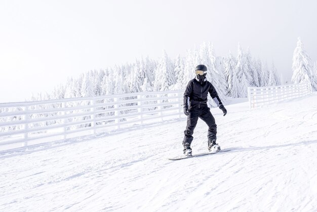 Kostenloses Foto snowboarder in bewegung, der den hügel im bergresort hinunter reitet