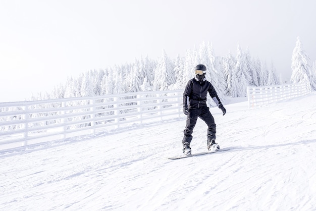 Snowboarder in Bewegung, der den Hügel im Bergresort hinunter reitet