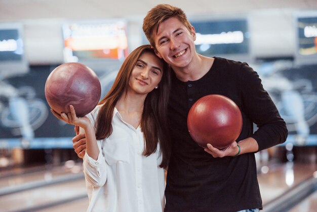 So ein schönes Volk. Glückliches Paar, das Bowlingkugeln in den Händen hält und gute Zeit im Verein hat