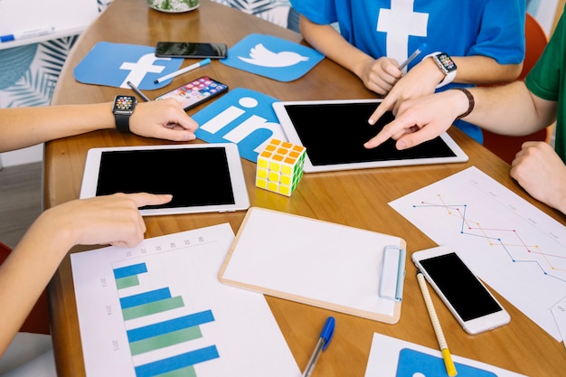 Social Media-Team, das digitale Tablette mit Social Media-Ikonen auf Schreibtisch verwendet
