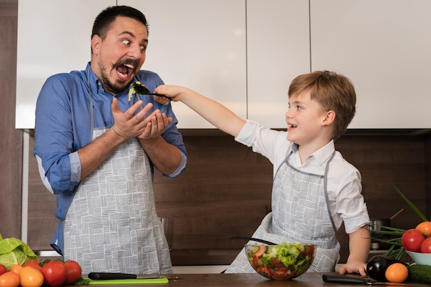 Kostenloses Foto sohn, der seinem vati gibt, um salat zu schmecken