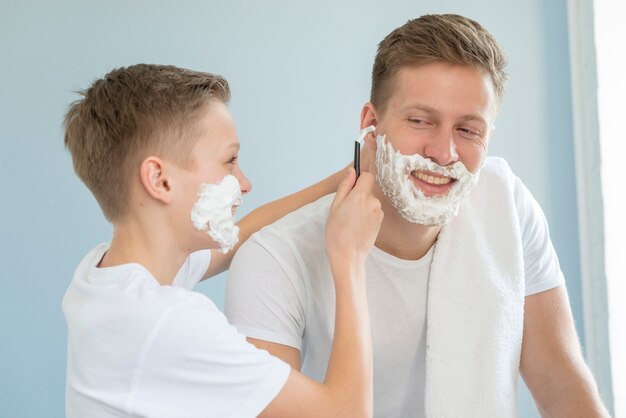 Sohn hilft seinem Vater bei der Rasur