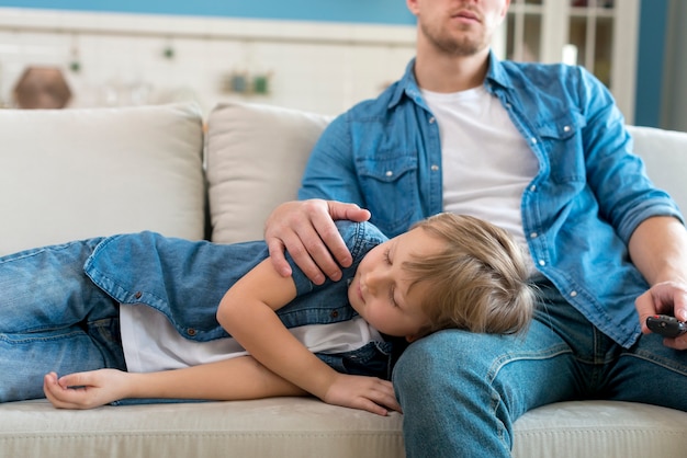 Sohn schläft auf Vaters Beinen