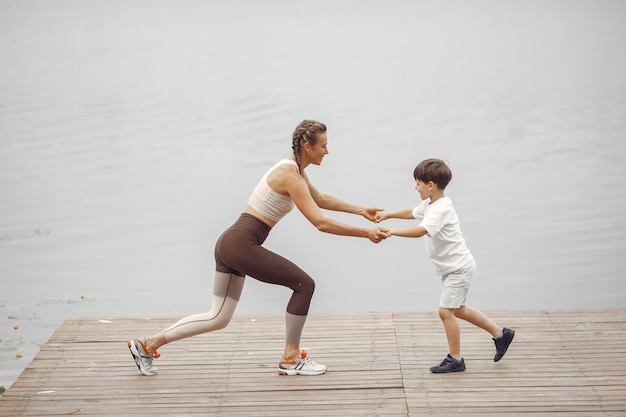 Sohn und Mutter machen Übungen im Sommerpark. Familie am Wasser.