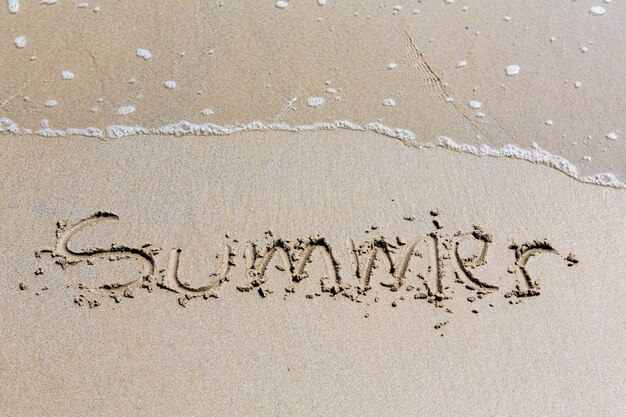 Sommer handgeschriebener Inschrift in Sand am Strand