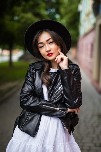 Sommer sonniges Lebensstilmodeporträt der jungen asiatischen Frau, die auf der Straße geht, niedliches trendiges Outfit tragend