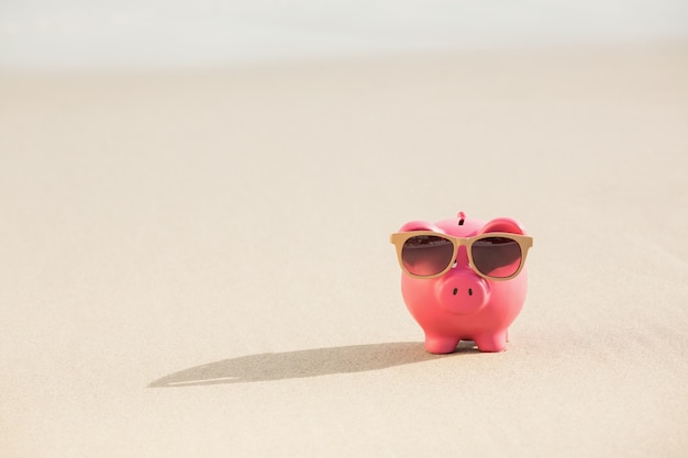 Sommer-Sparschwein mit Sonnenbrille auf Sand