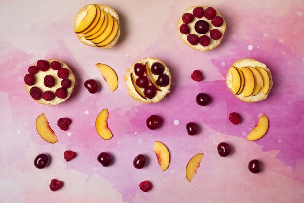 Sommerdesserts mit geschnittenen Früchten und Beeren auf rosa Hintergrund