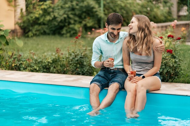 Sommerferien, Menschen, Romantik, Dating-Konzept, Paar, das Sekt trinkt, während die Zeit zusammen am Pool sitzt