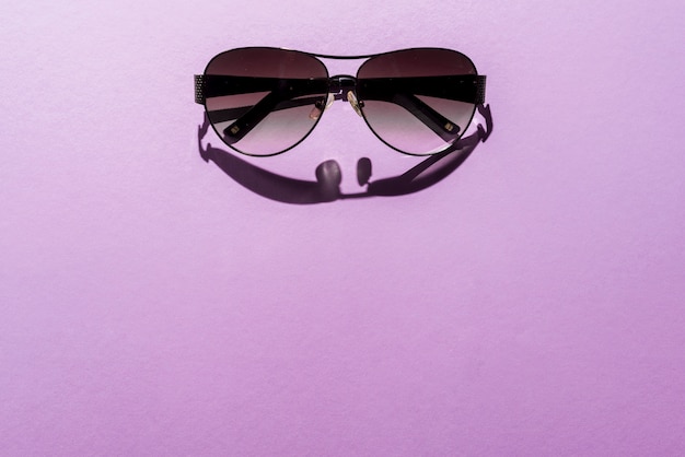 Sommerkonzept mit Sonnenbrille auf purpurrotem Hintergrund