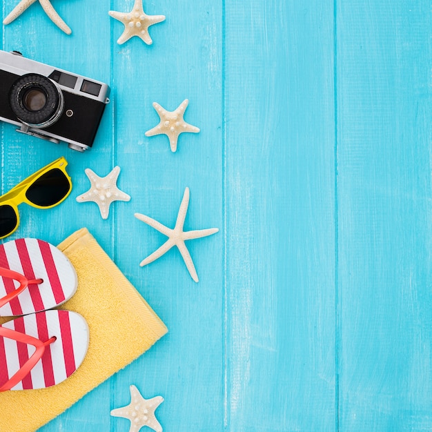 Sommerkonzept mit Weinlesekamera, Sonnenbrille, Tuch, Starfish auf blauem hölzernem Hintergrund