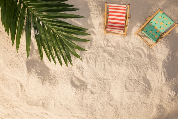 Kostenloses Foto sommerplan des palmeblattes und der kleinen deckchairs auf und