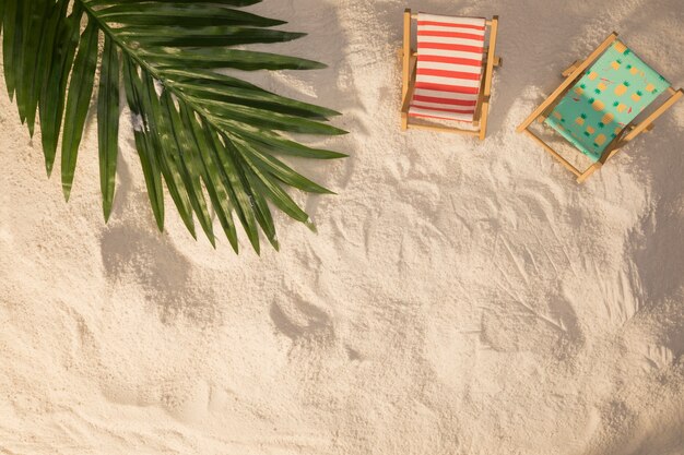 Sommerplan des Palmeblattes und der kleinen deckchairs auf und