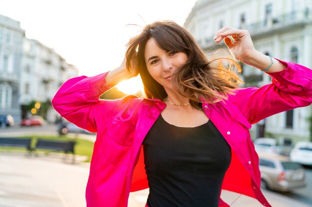 Sommerporträt einer verspielten, gut aussehenden Frau in stylischer rosa Jacke.