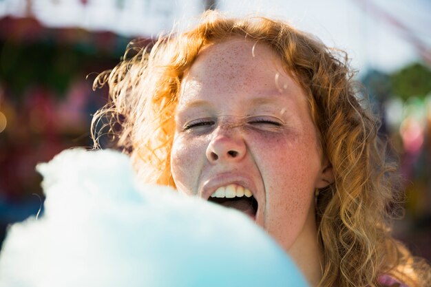 Sommersprossenfrau, die Zuckerwatte am Funfair isst