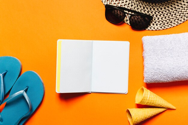 Sommerurlaubsortsachen und -notizbuch auf farbigem Hintergrund