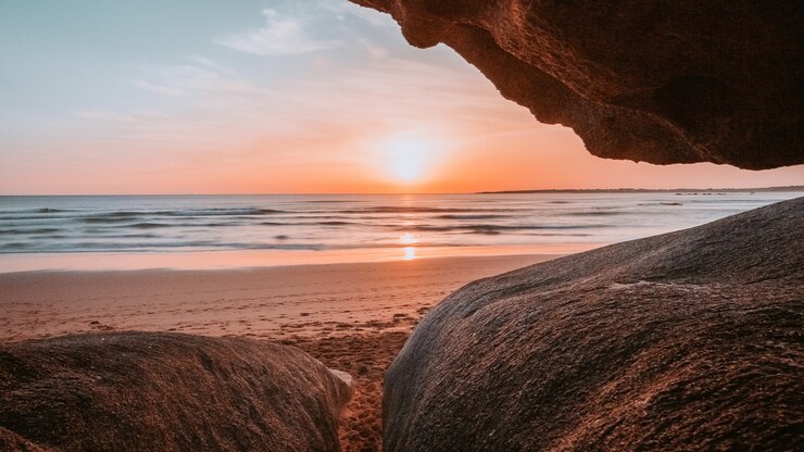 Kostenlose Foto sonne durch die klippen des strandes gesehen
