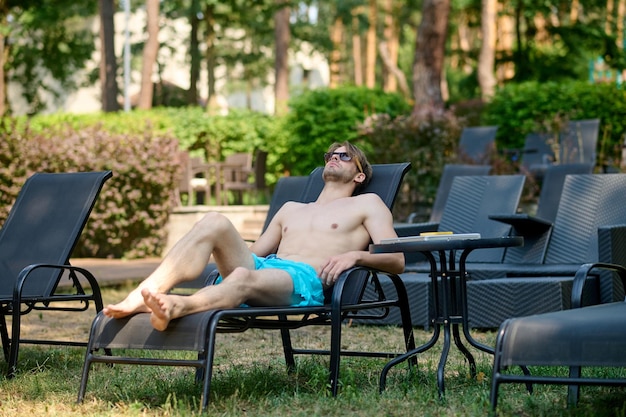 Sonnenbaden. Junger Mann in blauen Shorts sonnen sich und sehen entspannt aus