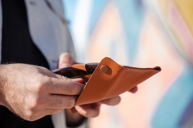 Kostenloses Foto sonnenbrille in eine gelbe ledertasche stecken