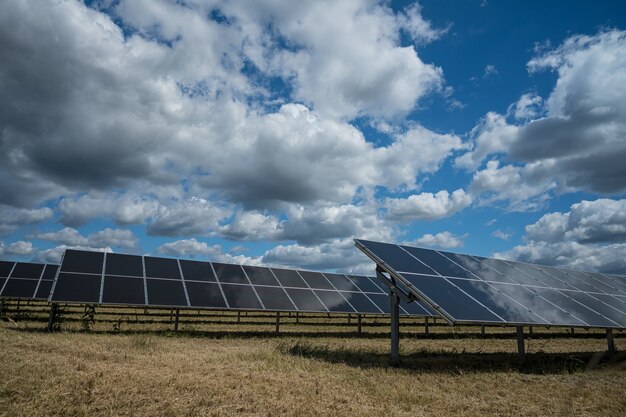 Sonnenkollektoren für erneuerbare Energie auf dem Feld unter dem Himmel voller Wolken