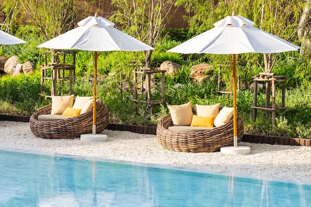 Sonnenschirm und Liegestuhl um Außenpool im Hotelresort mit Meeresmeerstrand und Kokospalme