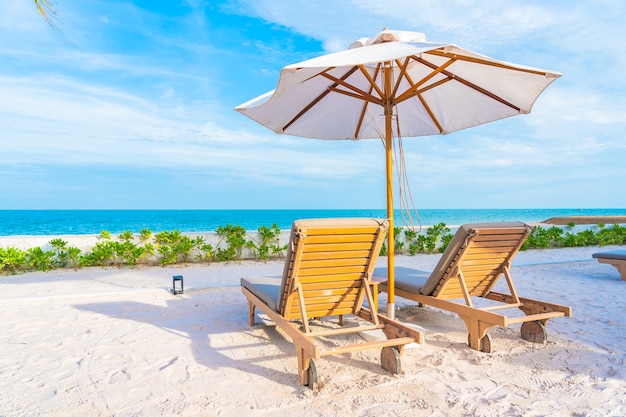 Sonnenschirm und Liegestuhl um Außenpool im Hotelresort mit Meeresmeerstrand und Kokospalme