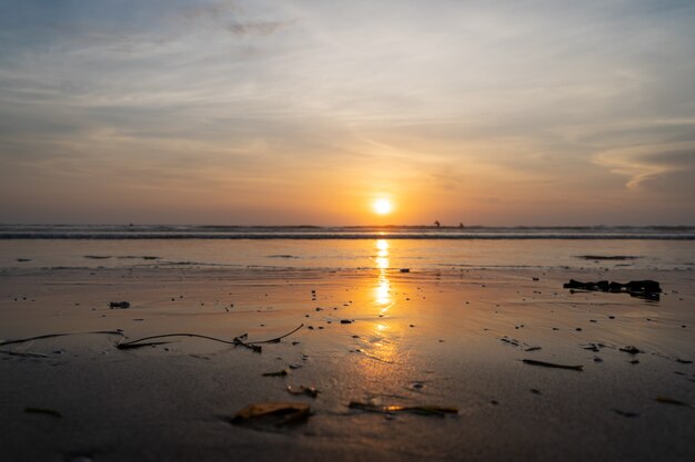 Sonnenuntergang über einem Meer mit den Wellen, die auf dem Strand brechen