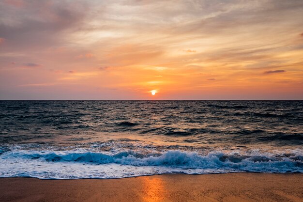 Sonnenuntergangsstrand und Seewelle