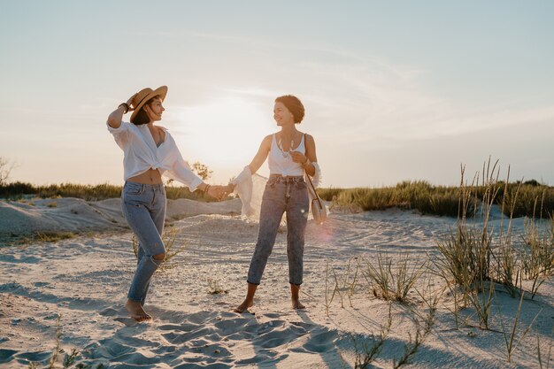 Sonnige glückliche zwei junge Frauen, die Spaß am Sonnenuntergangsstrand haben, schwule lesbische Liebesromantik