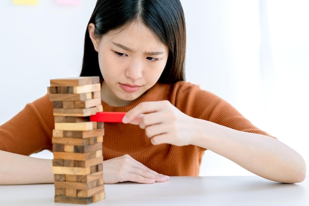 Sorge stress asiatische kluge frau versucht, konzept für strategieideen zum risikomanagement von holzstapeltürmen zu bauen und zu schützen