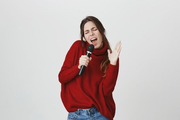 Sorglose Frau haben Spaß Karaoke, im Mikrofon singen