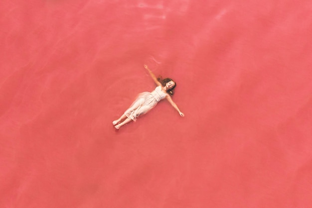 Sorglose Frau im Urlaub, die sich an rosa Wasser des Sees erfreut