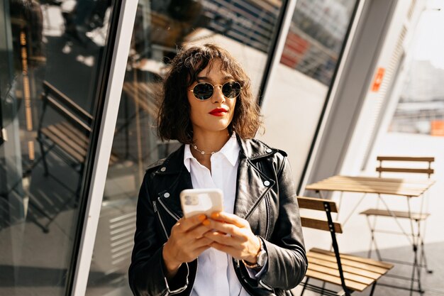 Sorglose junge Frau im trendigen Vintage-Outfit, das auf Terrasse sitzt