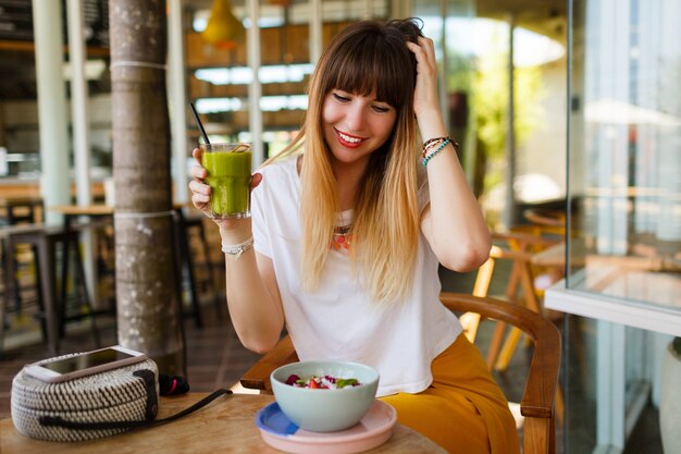 Sorglose lächelnde Frau, die gesundes veganes Frühstück isst.