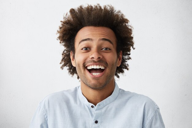 Sorgloser freudiger gutaussehender afroamerikanischer Mann mit buschiger Frisur
