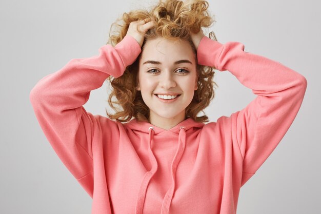 Sorgloses glückliches junges Mädchen, das lächelt und Haare berührt