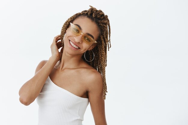 Sorgloses stilvolles afroamerikanisches Mädchen in der Sonnenbrille, die sich entspannt und glücklich fühlt
