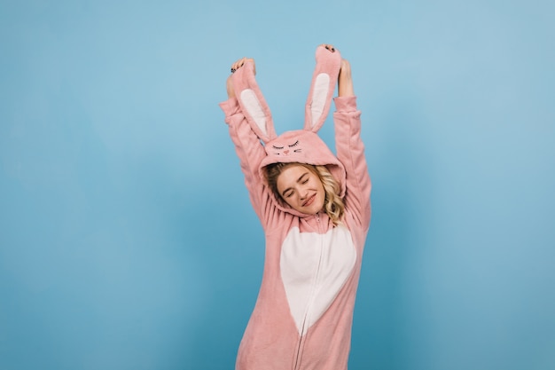 Sorgloses weibliches Modell, das in rosa kigurumi tanzt