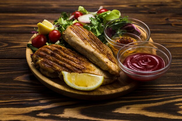 Soßen nahe gebratenem Huhn und Salat