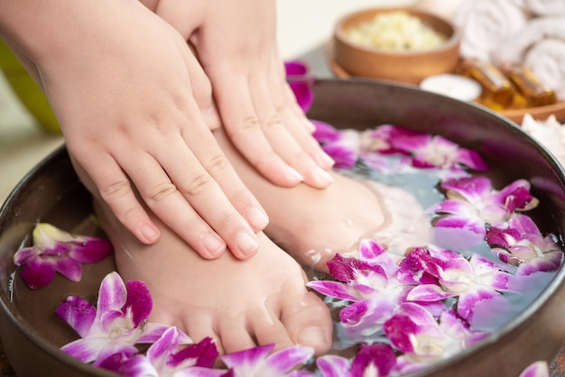 Spa-Behandlung und Produkt für weibliche Füße und Hand Spa. Orchideenblüten in Keramikschale.