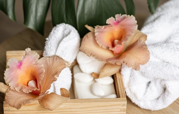 Spa-komposition mit körperpflegeprodukten in einer holzkiste und thailändischen orchideenblüten