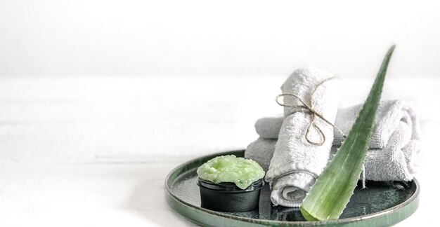 Spa-Stillleben mit Bio-Hautpflege, frischem Aloe-Blatt und Handtüchern.