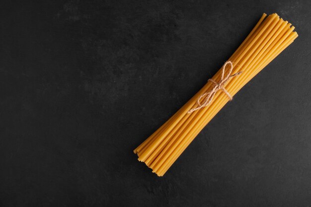 Spaghetti-Bündel auf schwarzem Hintergrund, Draufsicht.