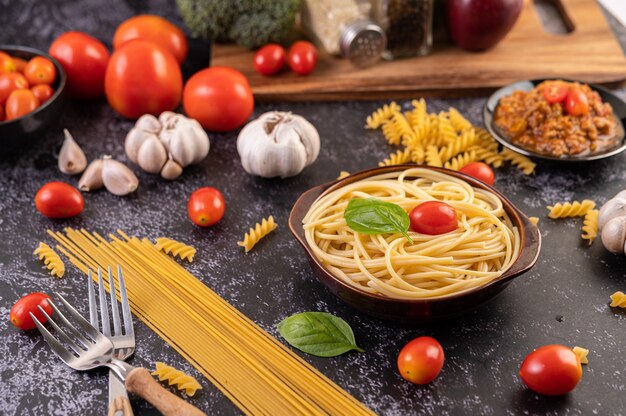 Spaghetti in einem grauen Teller mit Tomaten und Basilikum anbraten