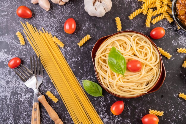 Spaghetti in einem grauen Teller mit Tomaten und Basilikum anbraten