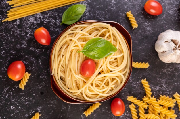 Spaghetti in einem grauen Teller mit Tomaten und Basilikum anbraten