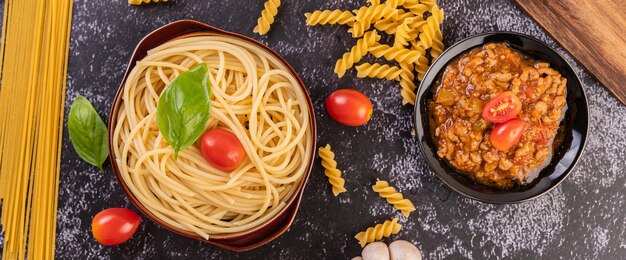 Spaghetti in einem grauen Teller mit Tomaten und Basilikum anbraten